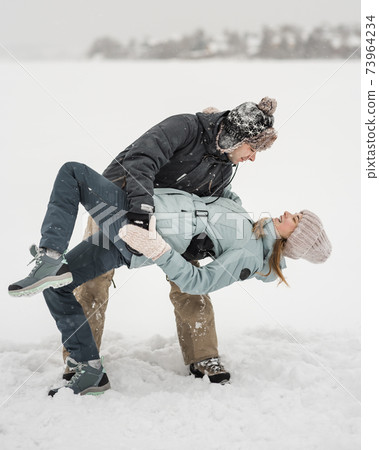 Happy couple dancing together in snow in winer Happy couple dancing together in snow in winer 73964234