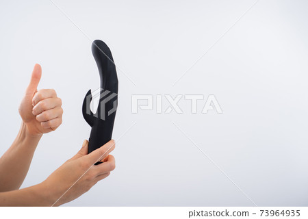 Faceless woman holding black dildo with clitoris stimulator on white background Faceless woman holding black dildo with clitoris stimulator on white background 73964935