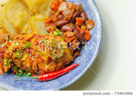 Chicken breast fillet with a chilli and cheese tomato sauce with crispy potato slices and minty bean salad on a blue plate Chicken breast fillet with a chilli and cheese tomato sauce with crispy potato slices and minty bean salad on a blue plate 73965966