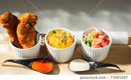 Breaded and herbed chicken breast fillet served with mash potatoes and tomato with onions Breaded and herbed chicken breast fillet served with mash potatoes and tomato with onions 73965997