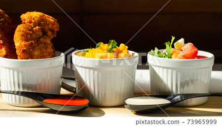 Breaded and herbed chicken breast fillet served with mash potatoes and tomato with onions 73965999