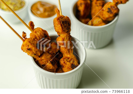 Satay chicken breast marinated in Indonesian style spices and grill on wooden skewers with dip peanut, ketchup, mustard Satay chicken breast marinated in Indonesian style spices and grill on wooden skewers with dip peanut, ketchup, mustard 73966118