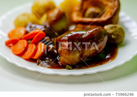 Roast potatoes and roast chicken breast in a chicken and white wine gravy with peas, carrots, pork and onion stuffing and a Yorkshire pudding 73966296
