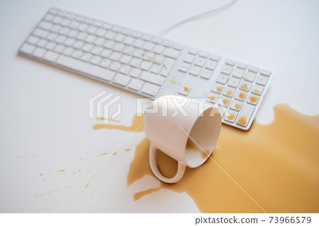Spilled black coffee on a computer keyboard at a white table Spilled black coffee on a computer keyboard at a white table 73966579