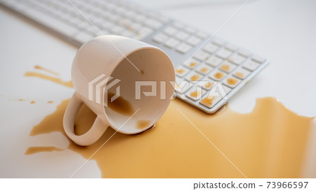 Spilled black coffee on a computer keyboard at a white table Spilled black coffee on a computer keyboard at a white table 73966597