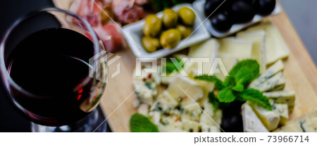 Red wine and set of different cheeses on a wooden board, delicious snack Red wine and set of different cheeses on a wooden board, delicious snack 73966714