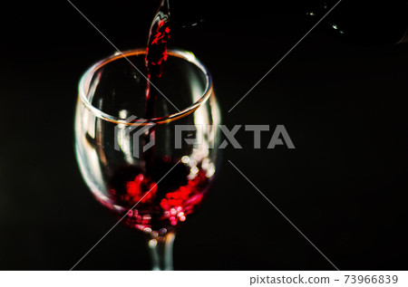 Pouring red wine in a glass, celebration of a moment with a glass of wine, exquisite liquor for gourmets Pouring red wine in a glass, celebration of a moment with a glass of wine, exquisite liquor for gourmets 73966839