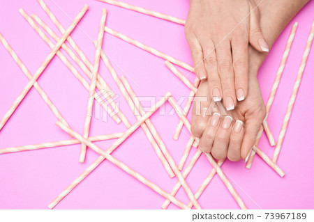 Beautiful Female Hands with French manicure over colorful paper background 73967189