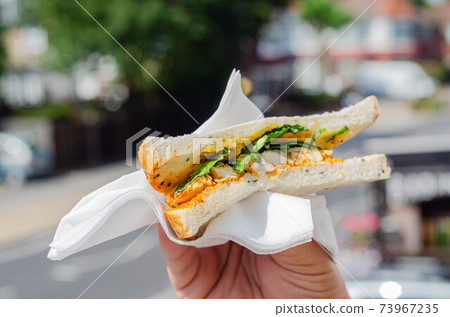 chicken breast in tikka spices, served with onion bhaji, crisp spinach and crunchy cucumber, all in sandwich 73967235