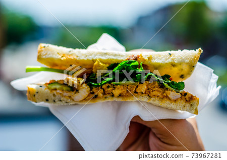 chicken breast in tikka spices, served with onion bhaji, crisp spinach and crunchy cucumber, all in sandwich 73967281