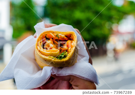 Chicken breast with piri piri sauce and lettuce in a chili tortilla wrap in the hand 73967289