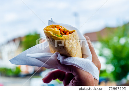 Chicken breast with piri piri sauce and lettuce in a chili tortilla wrap in the hand Chicken breast with piri piri sauce and lettuce in a chili tortilla wrap in the hand 73967295
