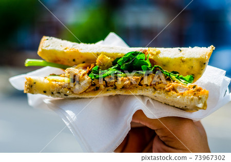 chicken breast in tikka spices, served with onion bhaji, crisp spinach and crunchy cucumber, all in sandwich 73967302