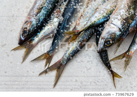 Whole raw organic mackerel fish with sea salt lying on a flat surface 73967629