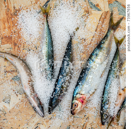 Whole raw organic mackerel fish with sea salt lying on a flat surface 73967656