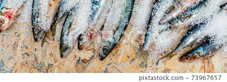 Whole raw organic mackerel fish with sea salt lying on a flat surface 73967657