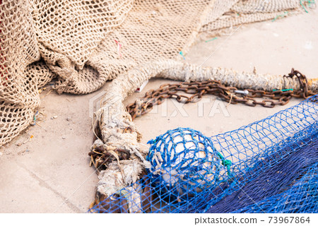 Industrial Fishing Equipment Fishnets and Fishing Lines lying on concrete in the port 73967864