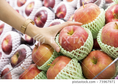 A female shopper holding an apple at a supermarket A female shopper holding an apple at a supermarket 73967971