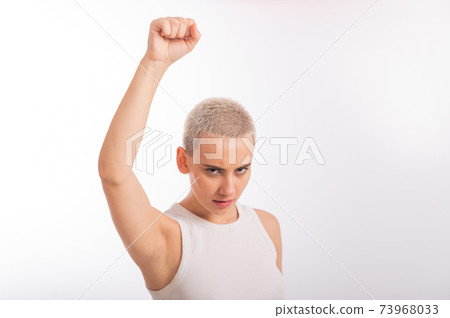 Young caucasian woman holding her fist up on a white background. A girl with short hair is fighting for rights Young caucasian woman holding her fist up on a white background. A girl with short hair is fighting for rights 73968033