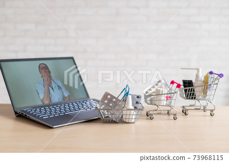 Online medicine and pharmacy concept. A female doctor conducts an online consultation and recommends medications. Mini trolley with tablets at the laptop. 73968115