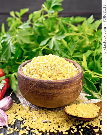 Bulgur in bowl with vegetables on dark board Bulgur in bowl with vegetables on dark board 73968135