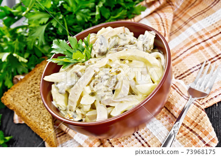 Salad with squid and champignons in bowl on napkin 73968175