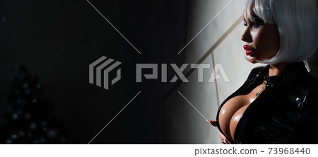 Sexy woman in a blonde wig and latex catsuit. Girl with big fake tits 73968440