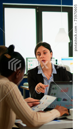 Multi-ethnic business team sitting at table in office center speaking about project 73970605