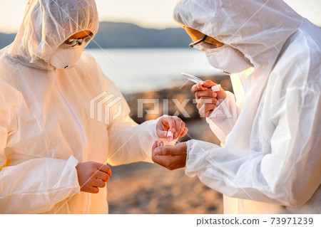 Young multi-ethnic scientists discussing water samples at beach 73971239