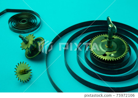 Clock springs with gears on a blue background, metal spirals, closeup Clock springs with gears on a blue background, metal spirals, closeup 73972106