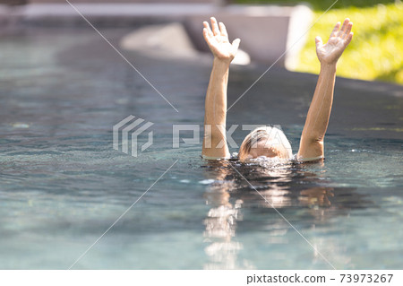 Asian senior people struggling underwater, hand peeking out of the water, female drowned in swimming pool, drowning elderly woman in swimming pool asking for help in dangerous situation 73973267