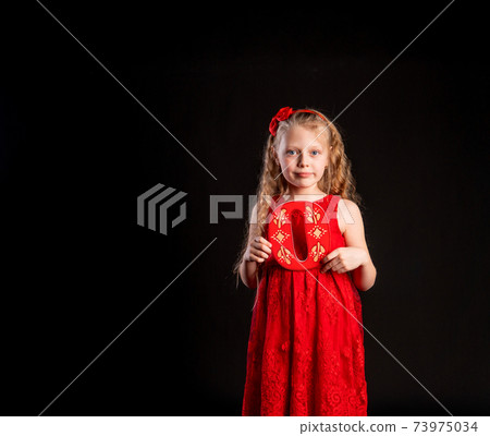 O holds a child holding in his hand the letter LOVE Valentine Valentine's background, , on the floor hearts a lovely layout. form a holiday. forever, joy in a red girl dress, barefoot 73975034