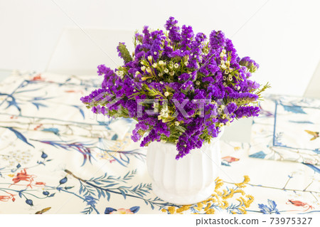 Cute flower arrangement with purple statice, decorating the dinner table Cute flower arrangement with purple statice, decorating the dinner table 73975327