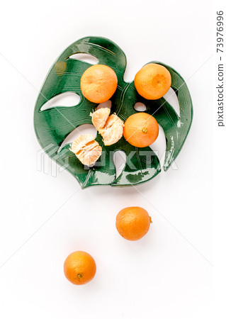 Ceramic plate-leaf Monstera with tangerines isolated on white background. Flat lay, top view. Ceramic plate-leaf Monstera with tangerines isolated on white background. Flat lay, top view. 73976996
