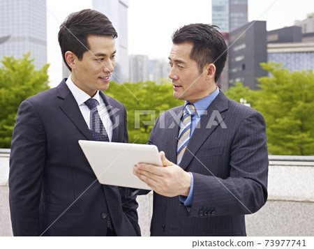asian businesspeople discussing business outdoor asian businesspeople discussing business outdoor 73977741