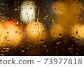 View of the night city through the wet car window with drops 73977818