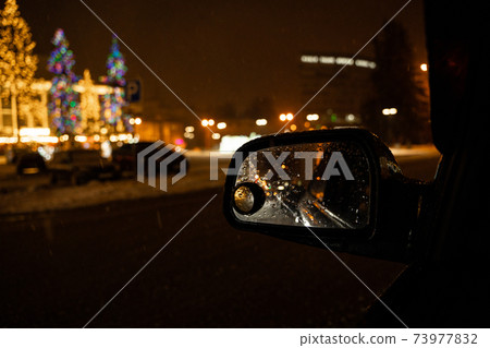View in the side mirror of the car of the night city 73977832