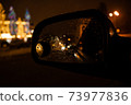 View in the side mirror of the car of the night city 73977836