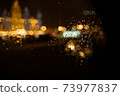 View of the night city through the wet car window with drops 73977837