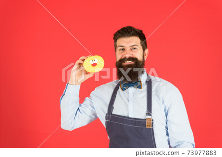 Bearded well groomed man in apron selling donuts. Donut Bearded well groomed man in apron selling donuts. Donut 73977883