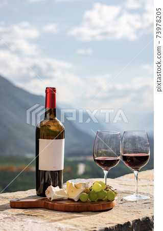 Glass of red wine and mountains on background. Swiss cheese and wine 73978205