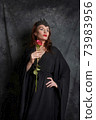 Woman in black dress with red rose 73983956
