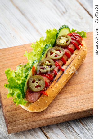 Jalapeno hotdog with ketchup on the wooden board 73985252