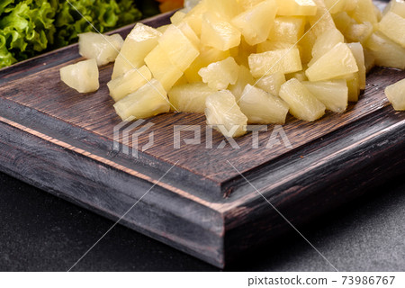 Pineapple canned with pieces on a wooden cutting board Pineapple canned with pieces on a wooden cutting board 73986767
