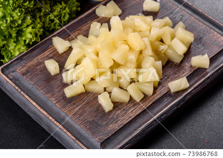 Pineapple canned with pieces on a wooden cutting board 73986768