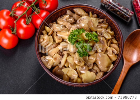 Fresh delicious spicy canned mushrooms with spices and herbs in ceramic dishes Fresh delicious spicy canned mushrooms with spices and herbs in ceramic dishes 73986778