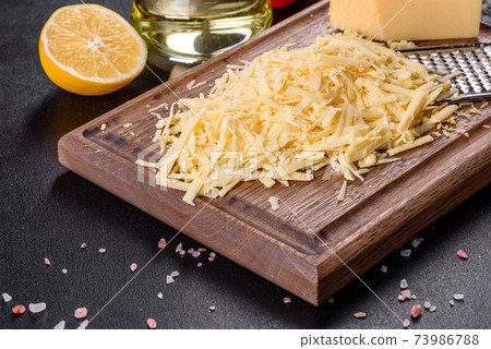 Fresh hard cheese grated on a large grater on a wooden cutting board Fresh hard cheese grated on a large grater on a wooden cutting board 73986788