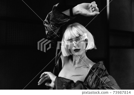 Blonde in cyberpunk style. Futuristic glasses on a woman. 73987814
