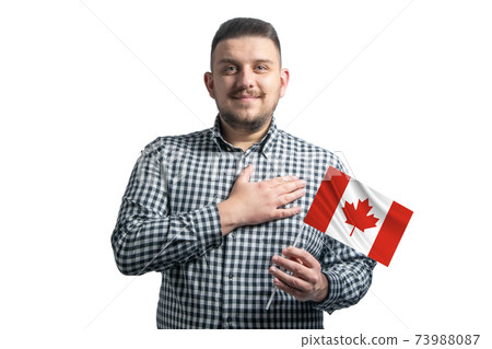 White guy holding a flag of Canada and holds his hand on his heart isolated on a white background With love to Canada White guy holding a flag of Canada and holds his hand on his heart isolated on a white background With love to Canada 73988087