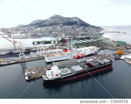 Aerial view of cargo ship and ferry under repair at Hakodate Dock, Hakodate City, Hokkaido in winter 73989758